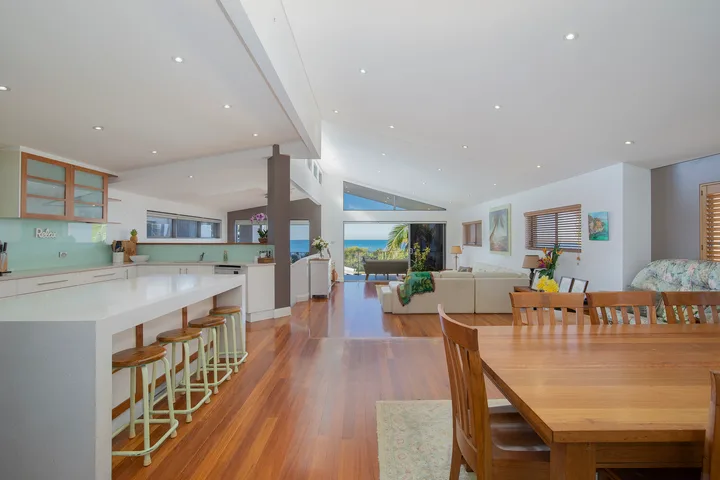 Una cocina y comedor de planta abierta dan a una sala de estar con vistas al mar.
