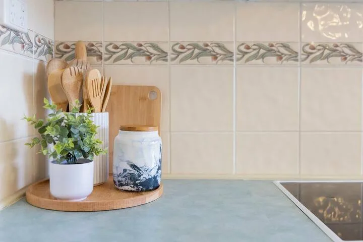 Una encimera de cocina con una planta en maceta, utensilios y un frasco.