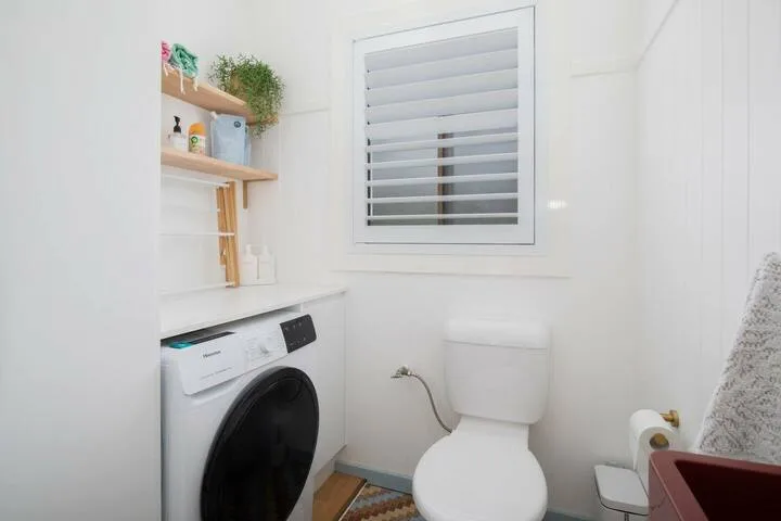 Un baño luminoso con inodoro, lavadora y ventana.