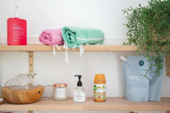 Estante de baño con toallas dobladas, artículos de aseo y una planta frondosa.