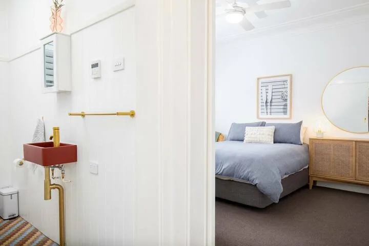 Un dormitorio con una cama y un mueble de frente tejido junto a un espejo de pared.