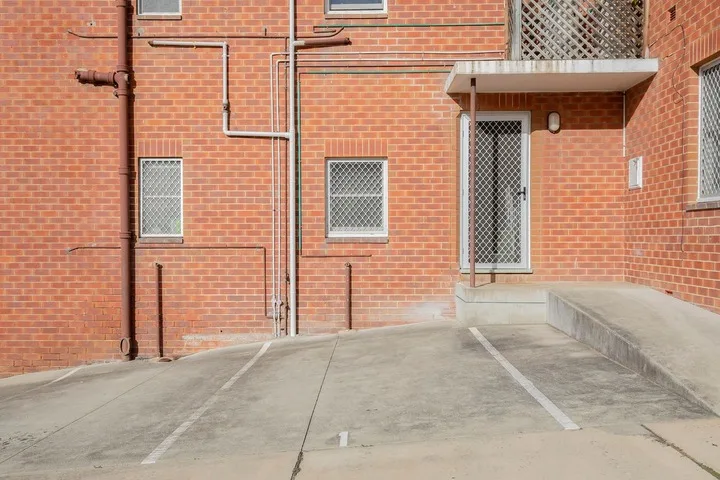 Una entrada exterior pavimentada junto a un edificio de ladrillo rojo.