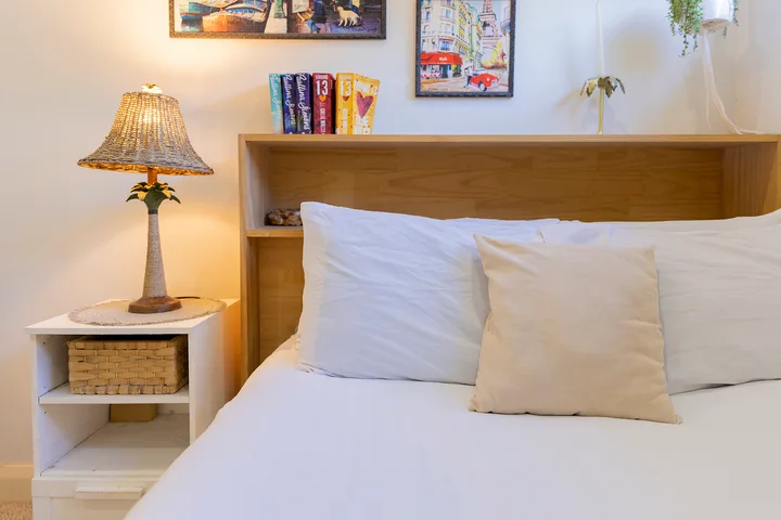 Un dormitorio con una cama blanca, almohadas y un cabecero de madera.