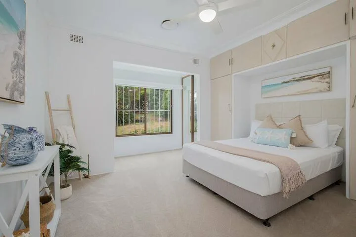 Un dormitorio luminoso tiene una cama grande, armarios empotrados y una ventana con vistas a la vegetación.