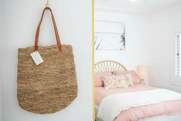 Un dormitorio luminoso con una cama rosa, ropa de cama blanca y una lámpara de noche.