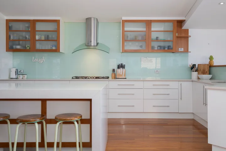 Una cocina luminosa con placa de cocción, campana extractora y barra.