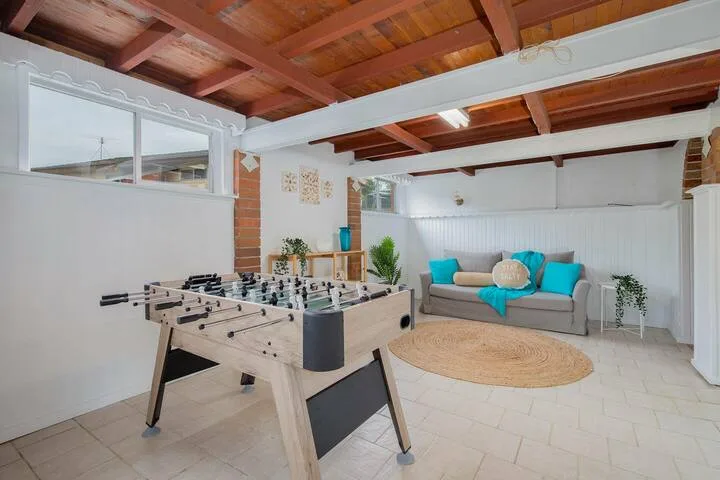 Sala de recreación con futbolín y asientos alrededor de una mesa baja.