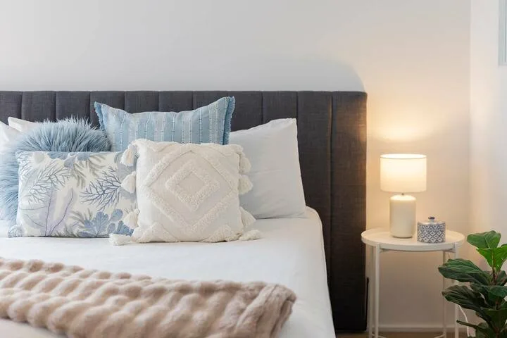 Un dormitorio con una cama bien tendida y una pequeña mesa de noche.