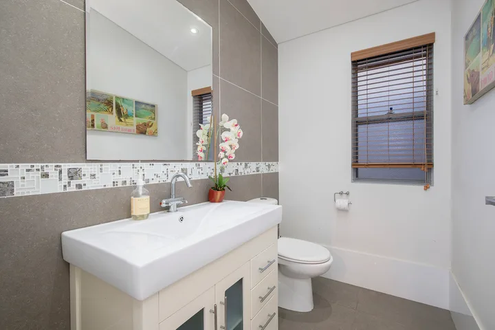 Un baño con un lavabo amplio, espejo e inodoro.
