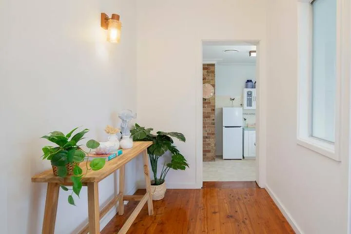 Un pasillo luminoso con una consola de madera y plantas en macetas.
