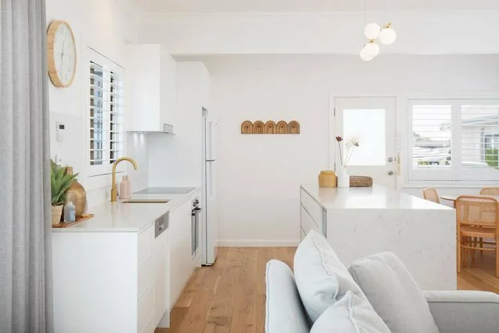 Una cocina y comedor luminosos con gabinetes blancos e isla.