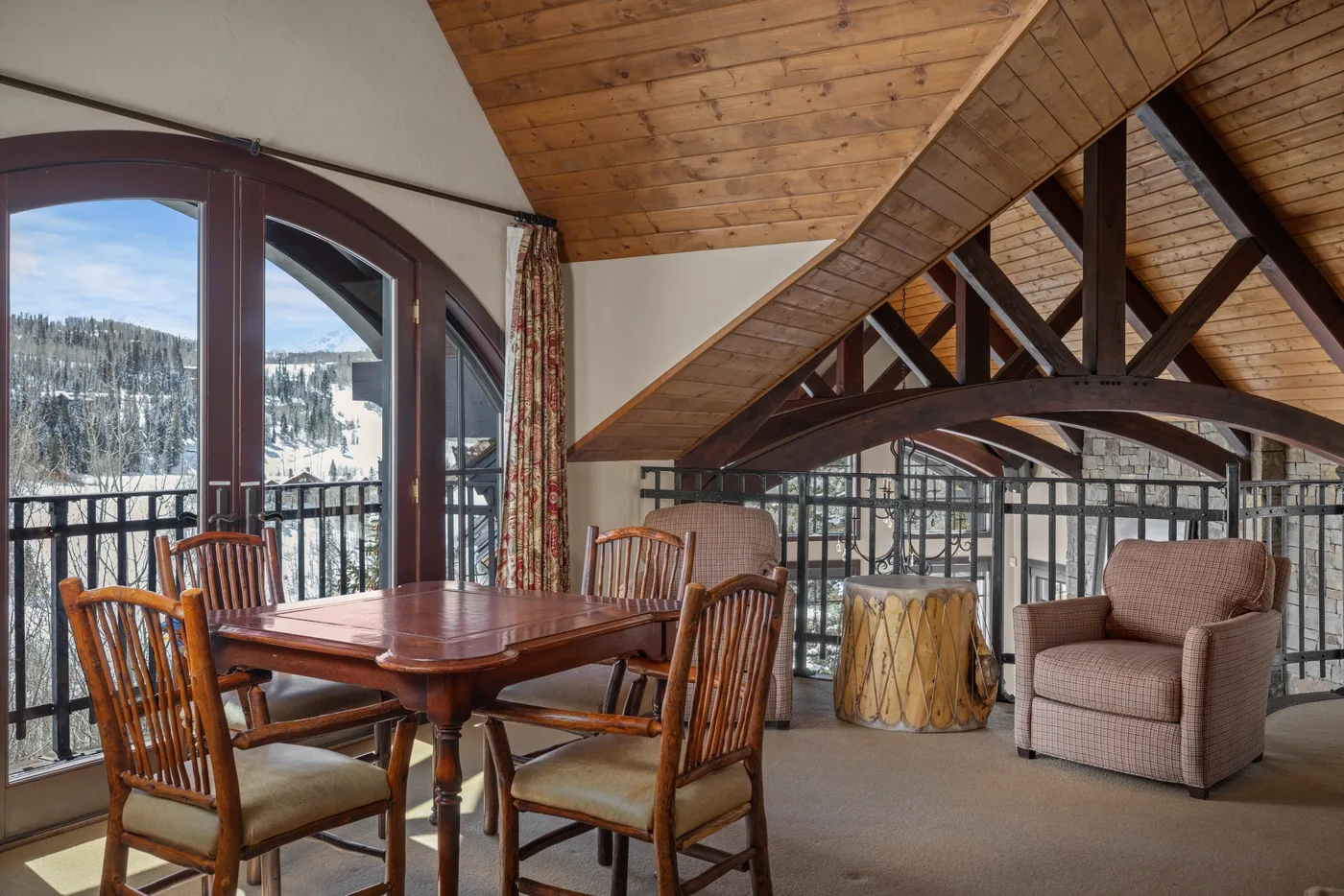 Una sala tipo loft con comedor, mesa de madera, asientos y grandes ventanas.