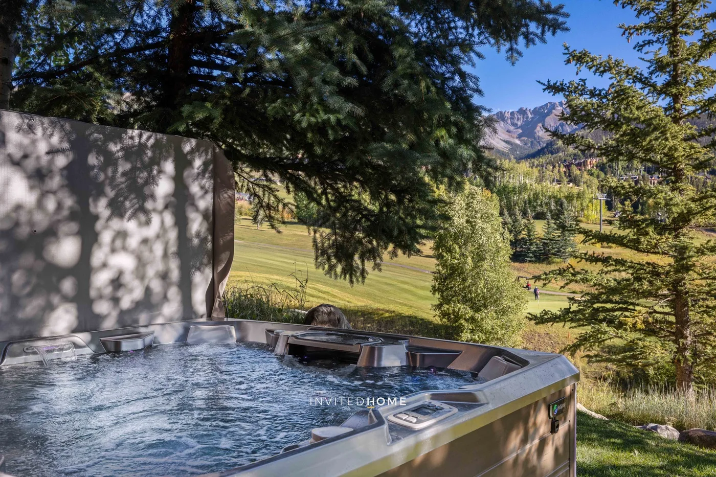 Una bañera de hidromasaje al aire libre tiene vistas a un paisaje de hierba y montañas lejanas.