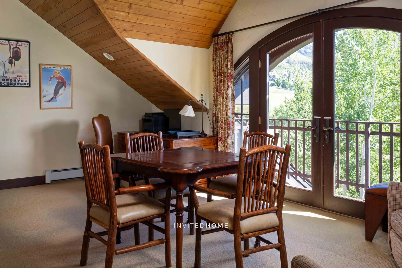 Un comedor con una mesa y sillas de madera junto a grandes puertas de vidrio.