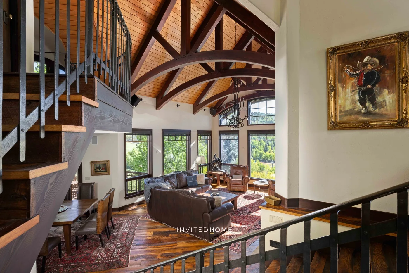 Una sala de estar abovedada con vigas de madera a la vista y grandes ventanales.