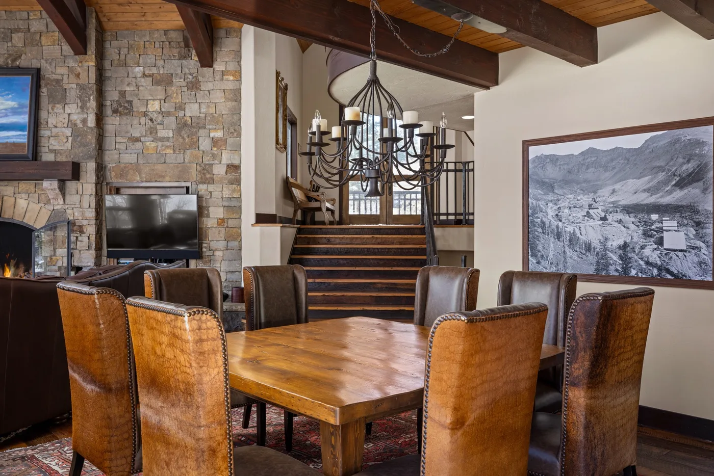 Comedor con una mesa de madera y asientos bajo vigas expuestas.