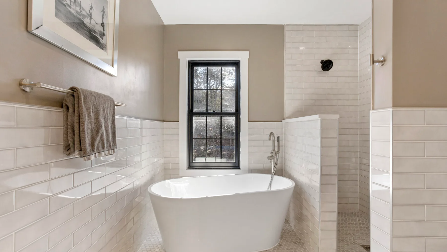 Un baño con una bañera exenta, paredes con azulejos y una ventana.