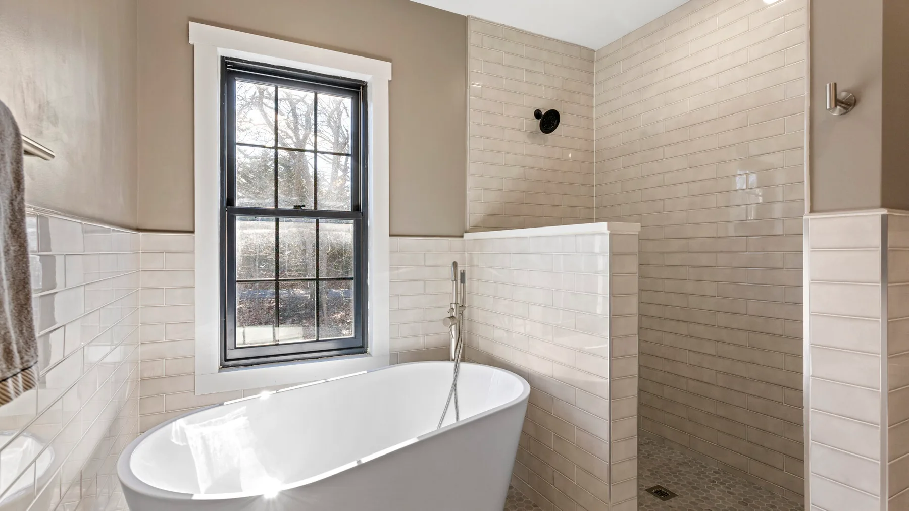 Un baño con una bañera exenta junto a una ducha con azulejos.