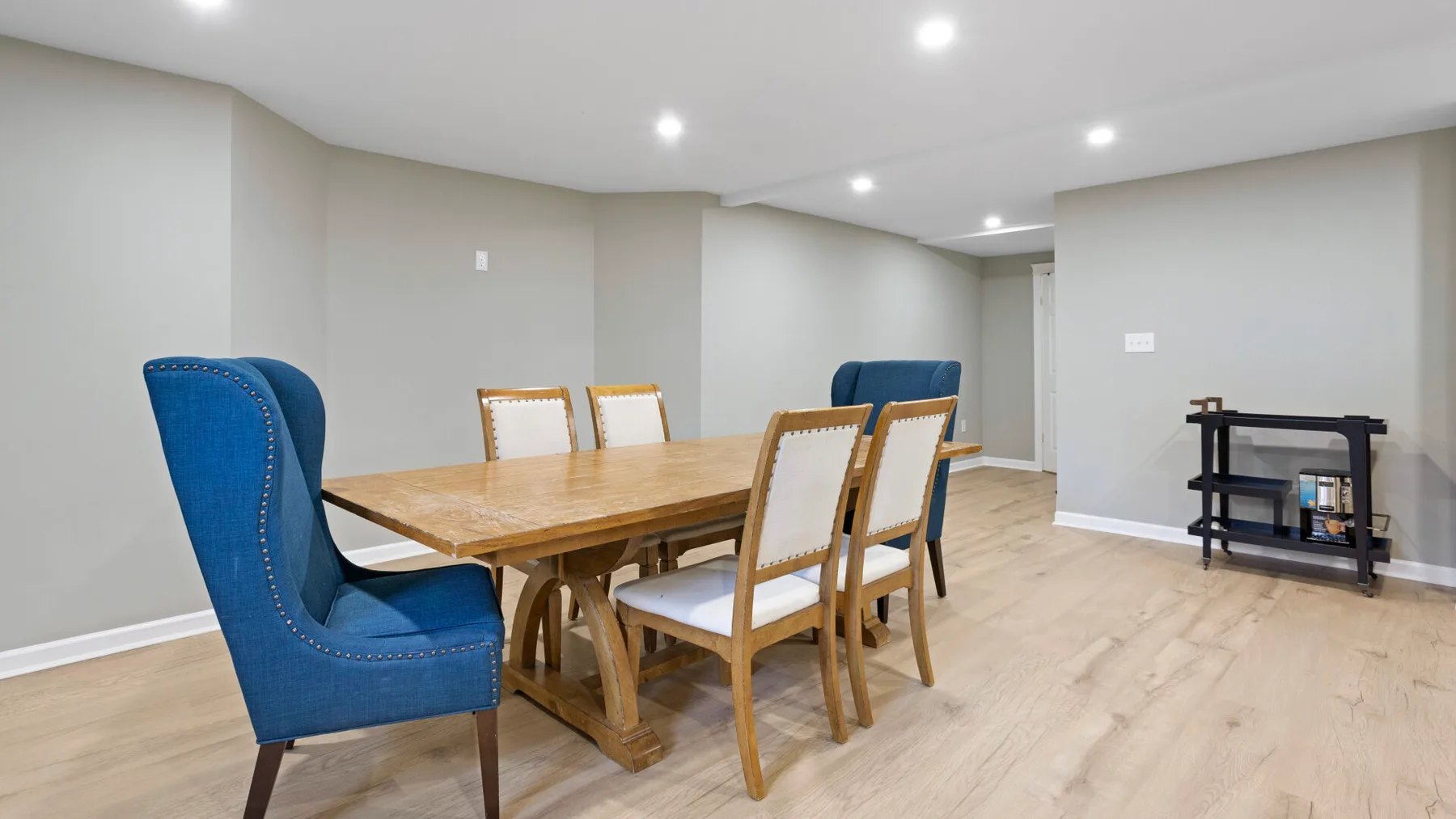 Un comedor con una mesa y sillas de madera, asientos azules y piso claro.