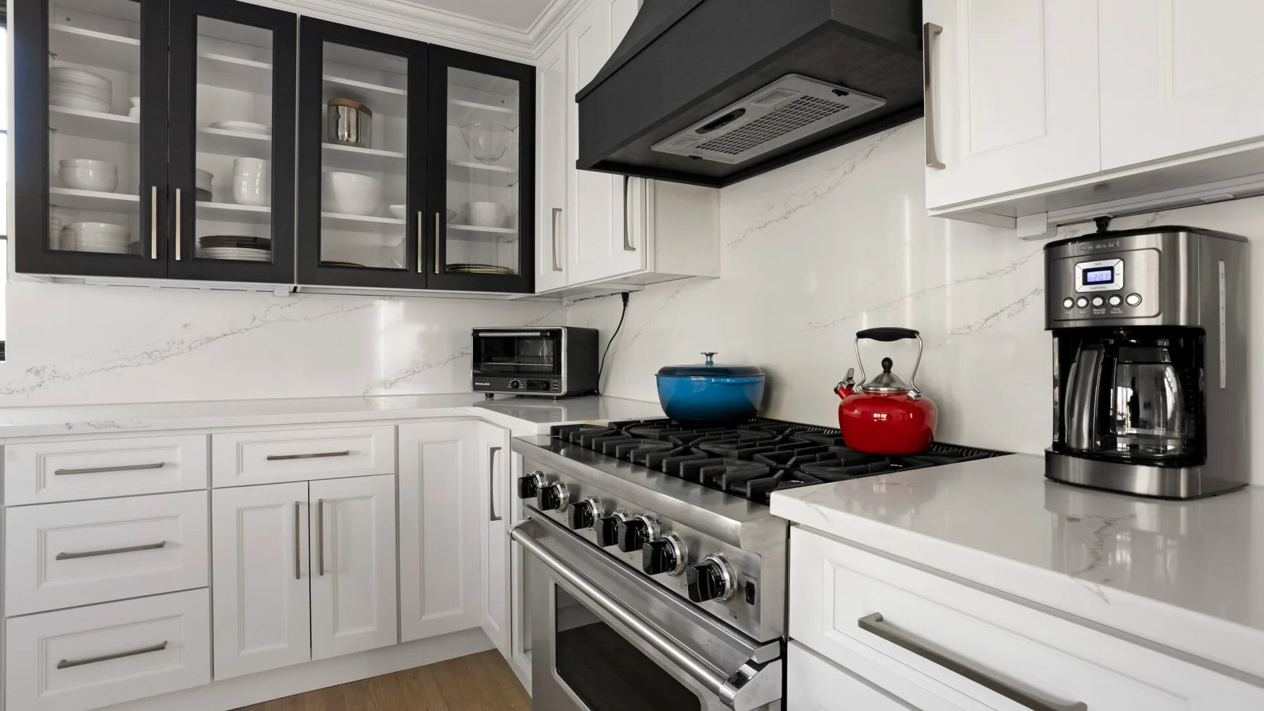 Una cocina luminosa con una estufa de acero inoxidable y gabinetes negros con puertas de vidrio.