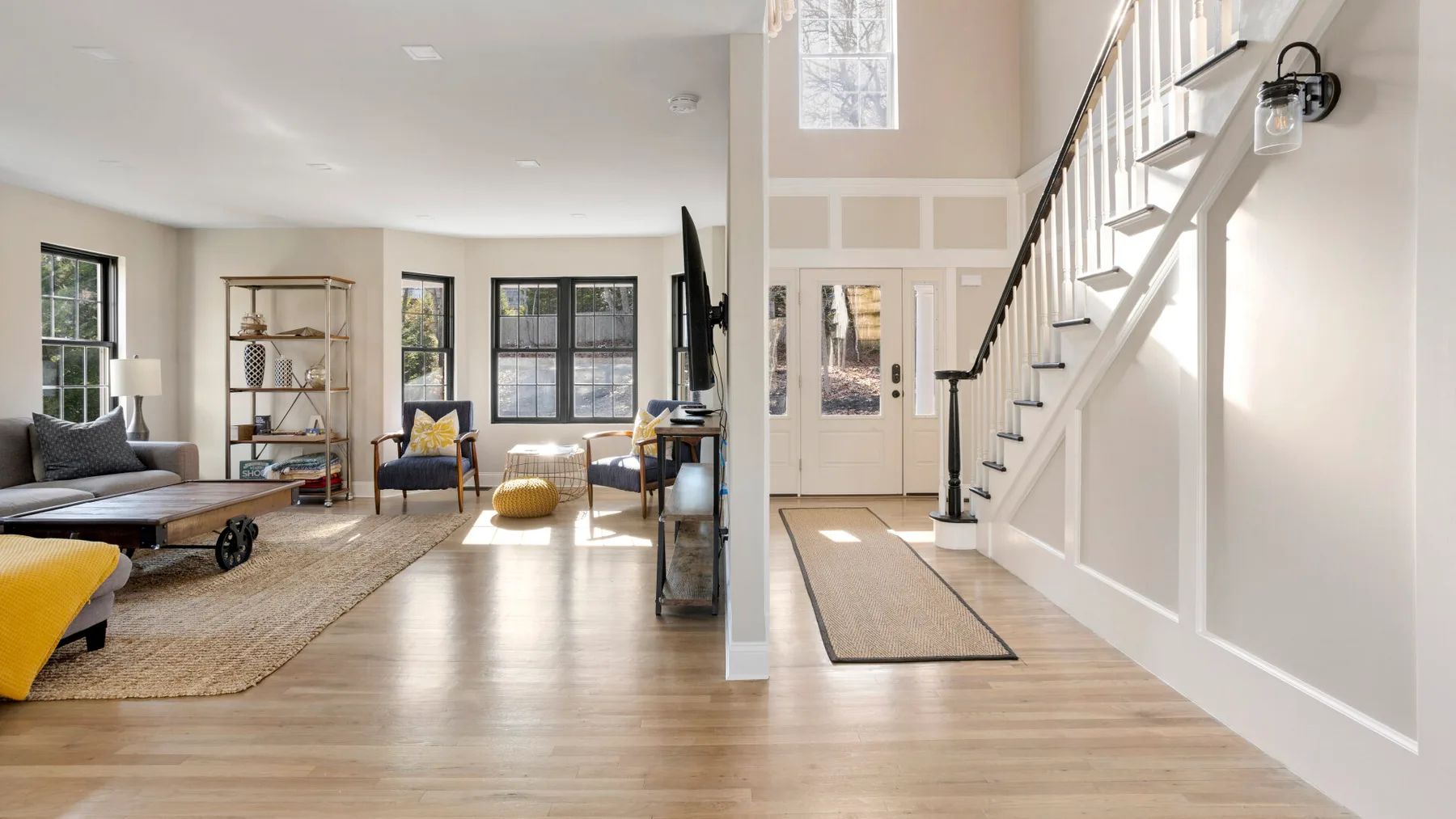 Una sala luminosa da a una escalera, con asientos y una ventana grande.