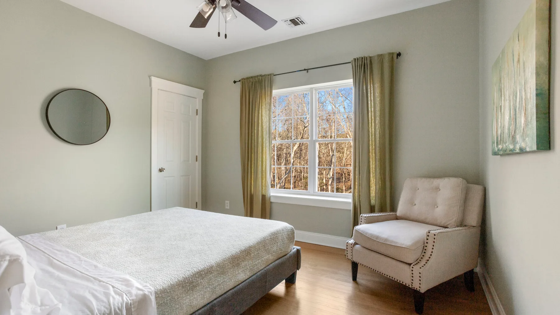Un dormitorio con una cama, una ventana y un sillón tapizado.