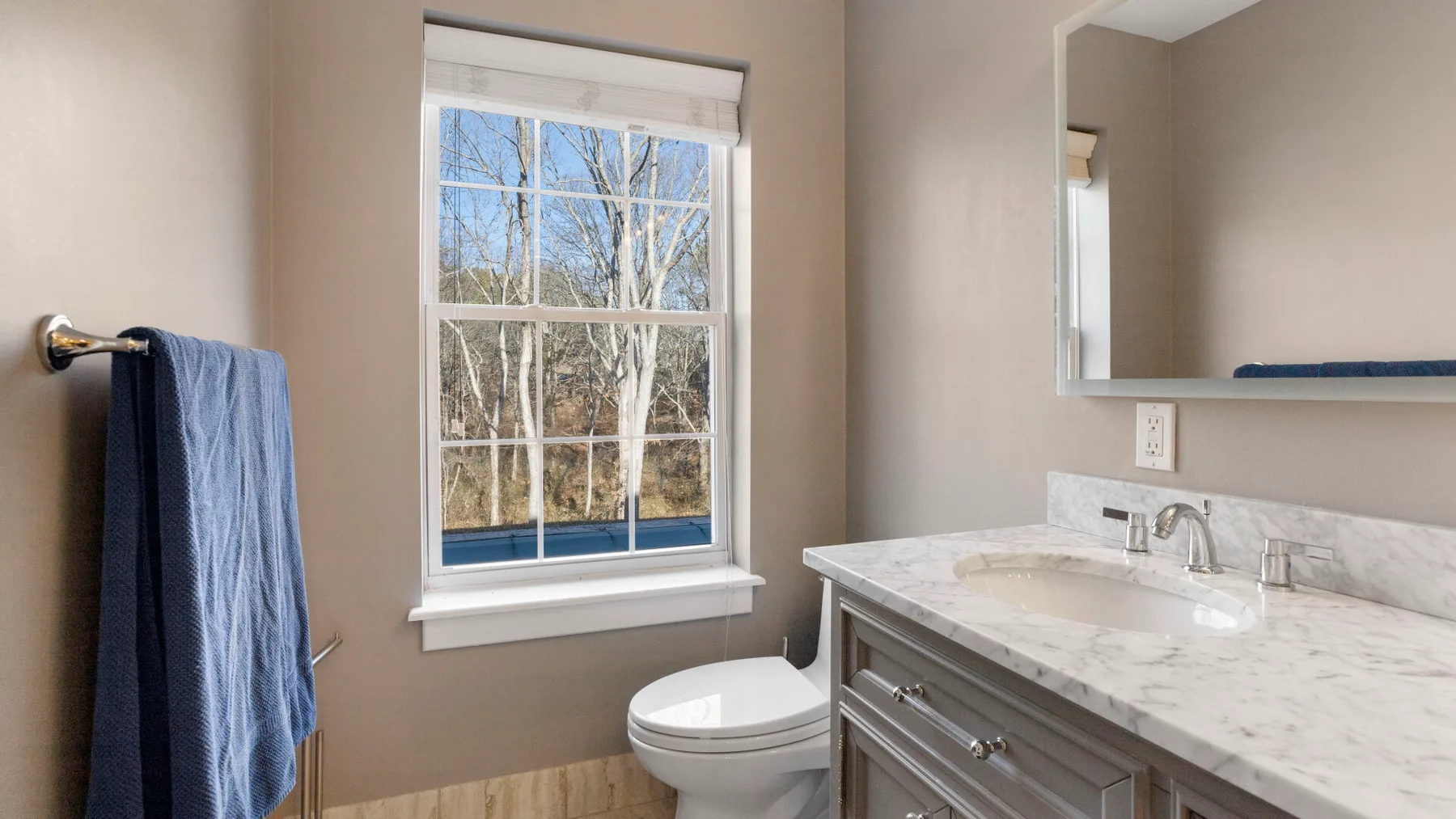 Un baño con ventana, inodoro y tocador.
