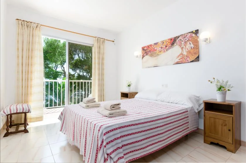 A bright bedroom with a striped bedspread and a large window.