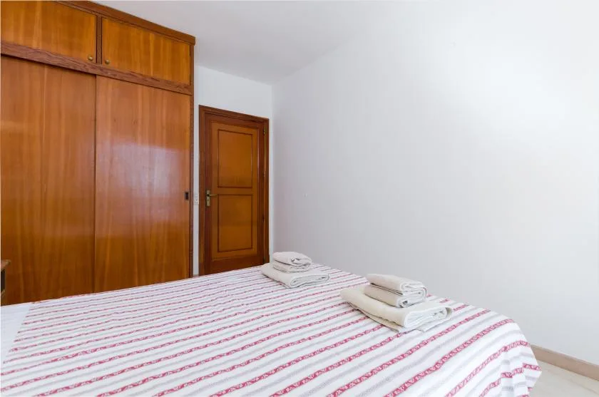 A bedroom with a striped bedspread and folded towels.