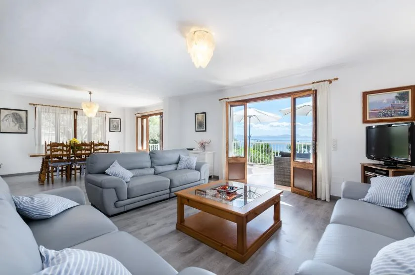 A bright living room with gray seating and glass doors opening onto a balcony.