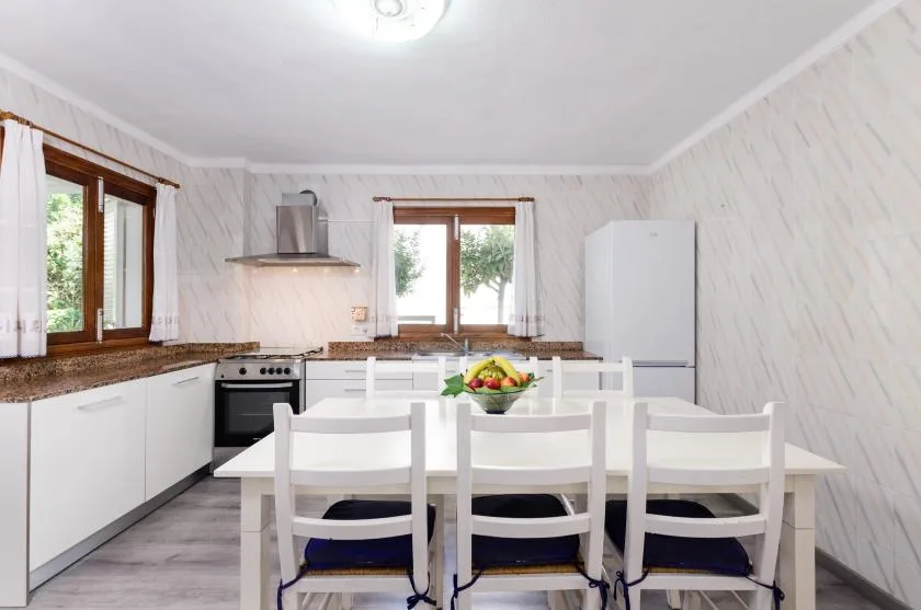 A kitchen and dining area with white cabinets, a table, and chairs.
