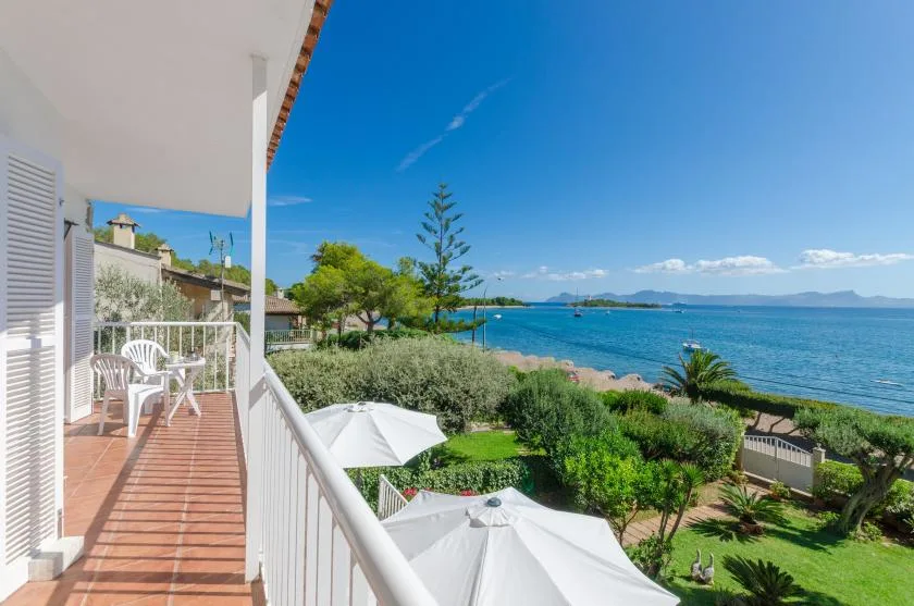 A covered balcony overlooks a landscaped garden and the sea.