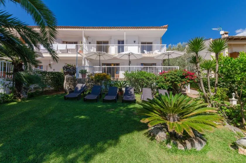 A white two-story building overlooks a landscaped garden with lounge seating.