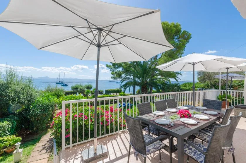 An outdoor dining terrace with a set table, patio seating, and views of the water.