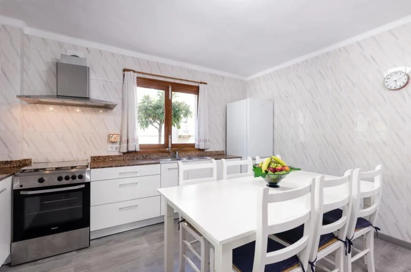 A bright kitchen with white cabinets, a dining table, and chairs.