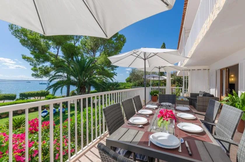 An outdoor dining terrace overlooks the water, with a table beneath white umbrellas.