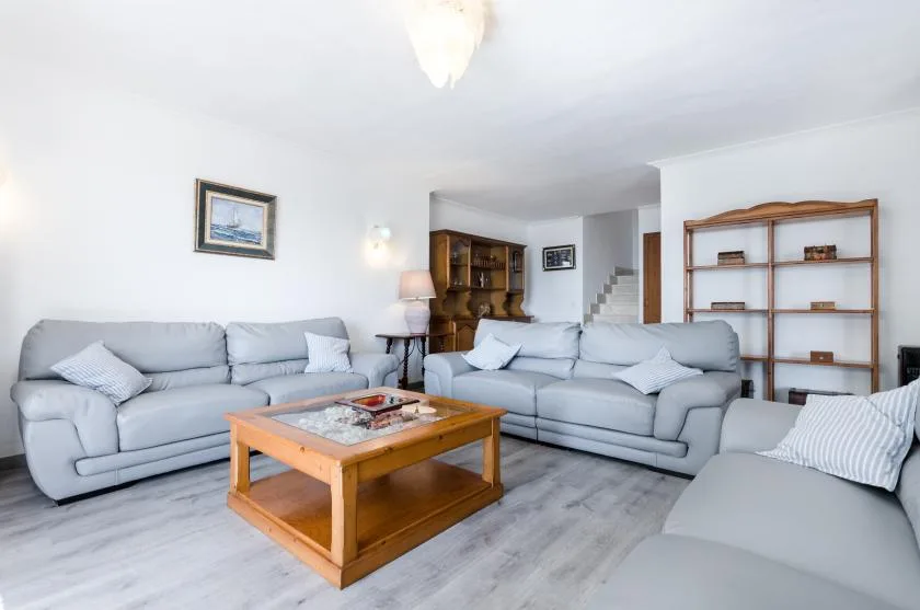A bright living room with light-colored seating around a wooden coffee table.
