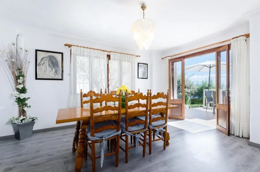 A dining area with a wooden table and chairs beside open doors to a patio.