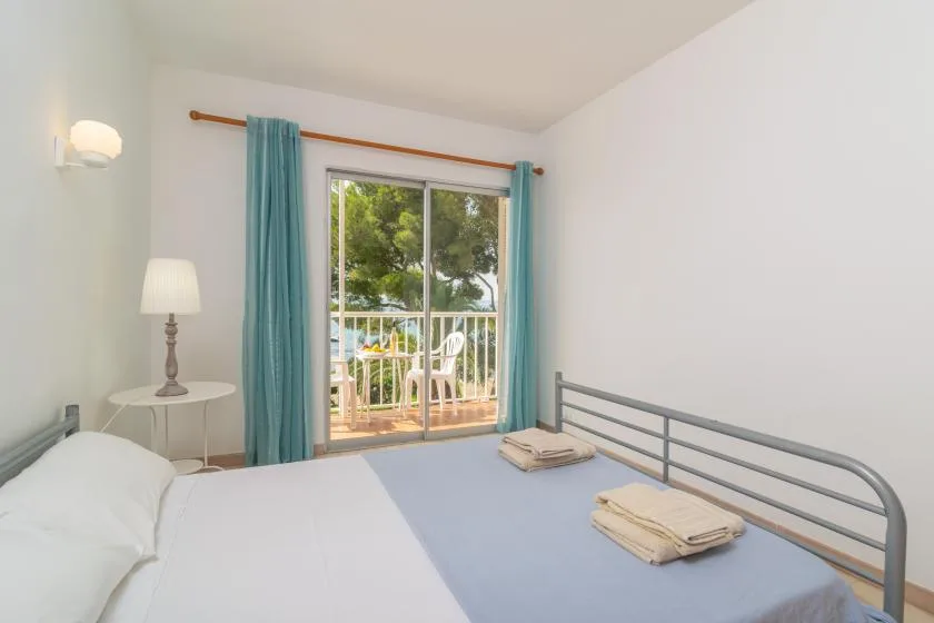 A bedroom with a bed, teal curtains, and a sliding glass door to a balcony.
