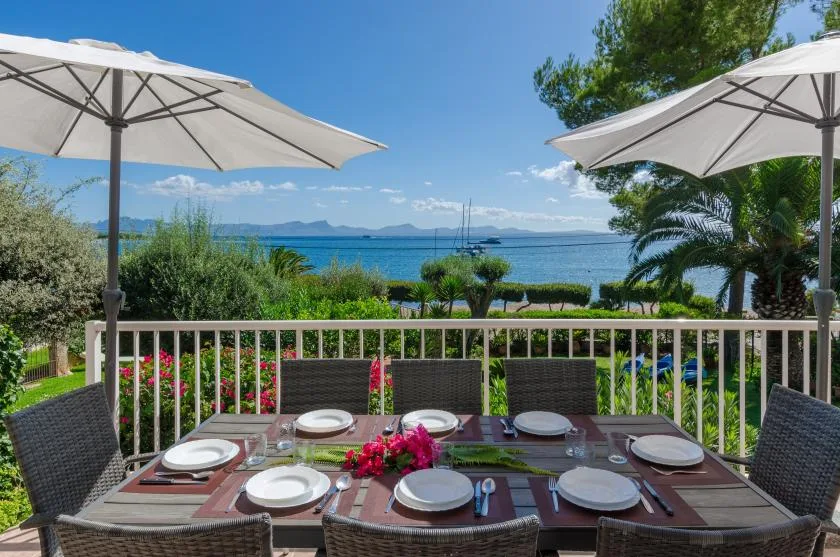 An outdoor dining area overlooks the sea, with table settings and patio umbrellas.