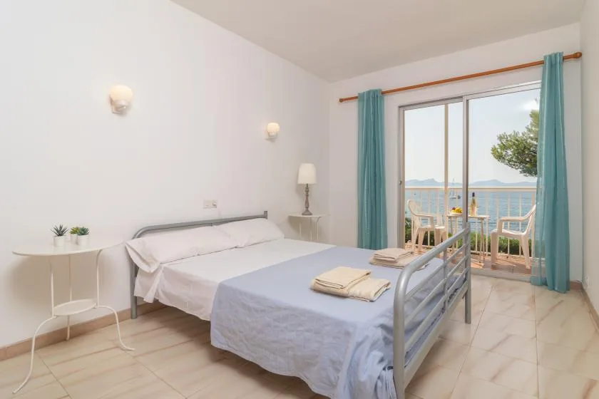 A bedroom with two beds beside a large window opening onto a balcony.