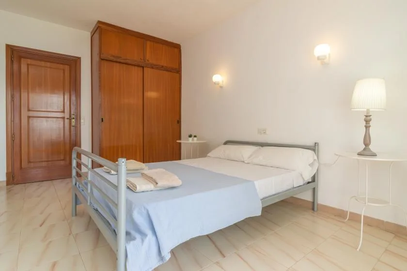 A bedroom with a neatly made bed and wooden wardrobe.