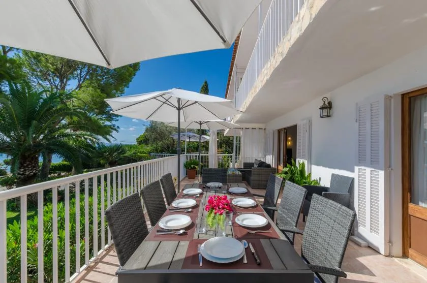 An outdoor dining area on a sunny terrace overlooks leafy greenery.