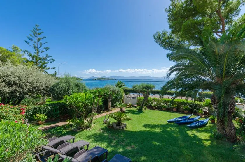 A landscaped garden with green lawn and trees overlooking the sea.