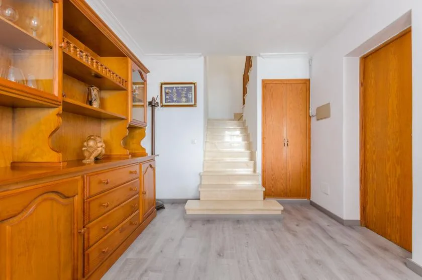 An interior entryway with a staircase, wooden storage, and doors.