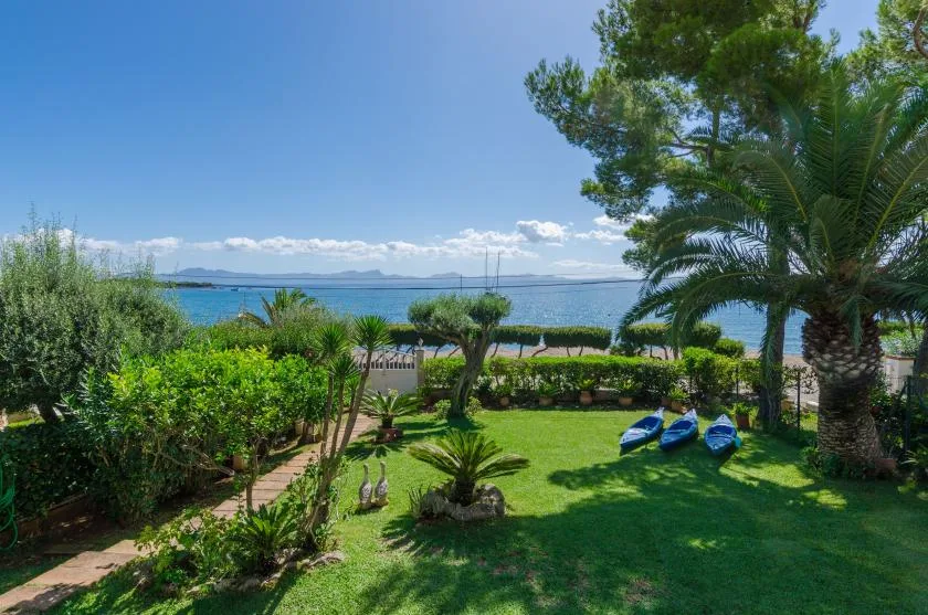 A landscaped garden overlooks the sea, with kayaks resting on the lawn.