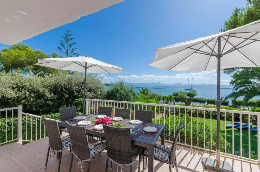 An outdoor dining terrace overlooks the water beneath large umbrellas.