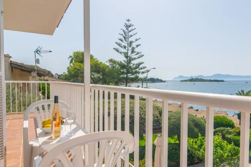 A balcony with outdoor seating overlooks the beach and ocean.