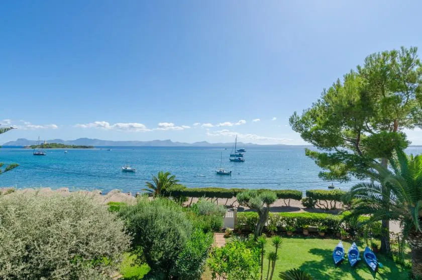 A landscaped seaside garden overlooks a calm bay with boats on the water.