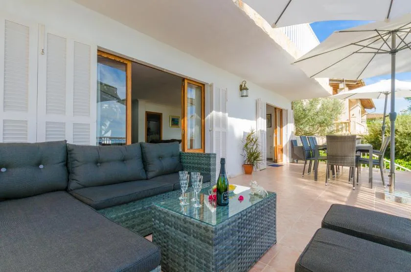 A sunny outdoor patio with cushioned seating, a glass coffee table, and a dining area.